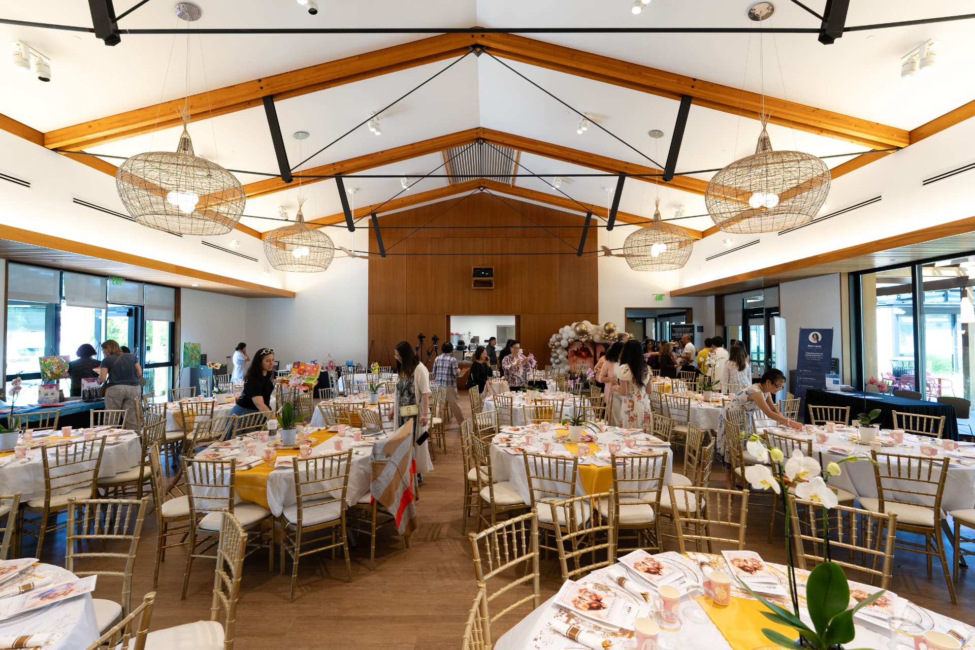 Tables set with gold chairs and floral centerpieces before the screening